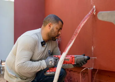 A man using a drill to work on an outdoor installation.