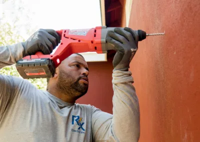 A man using a cordless drill to work on an outdoor wall.