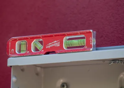 A spirit level resting on top of a metal frame against a red background, indicating a horizontal alignment.