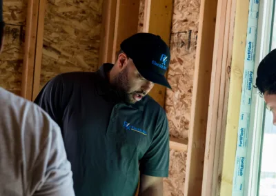 A man in a work shirt reviews architectural plans at a construction site.