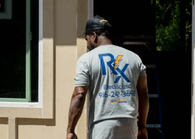 A construction worker wearing a hat and a company t-shirt while standing on wooden steps at a building site.