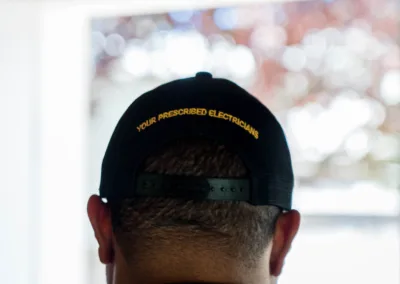 Rear view of a person wearing a cap with the text "your prescribed electrician.