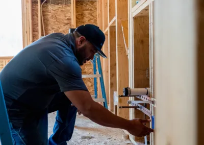 A man kneeling and working on a construction site, consulting plans.