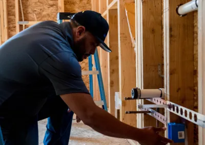 Construction worker measuring a wooden frame at a construction site.