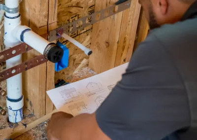 A plumber consulting a blueprint while working on pipes.