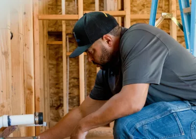 A construction worker measures a wooden beam on a construction site.