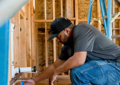 A construction worker measuring a wooden frame at a building site.