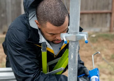 A technician applying sealant to secure equipment outdoors.