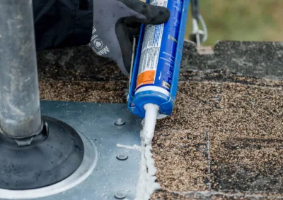 Applying sealant to a roof vent to prevent water leakage.