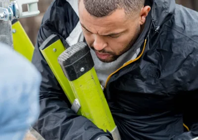 A man applying sealant from a caulk gun to a rooftop fixture.