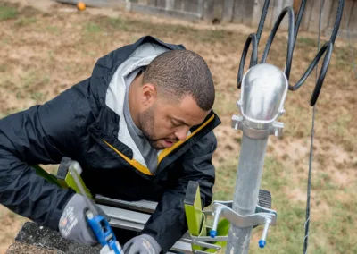 A person applying sealant to a vent pipe on a rooftop.