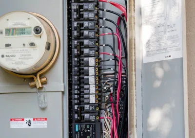 Open residential electrical panel displaying circuit breakers and wiring with a schematic diagram attached to the door.