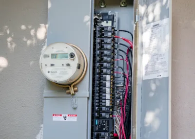 An open residential electrical breaker box with an electricity meter mounted on the side.