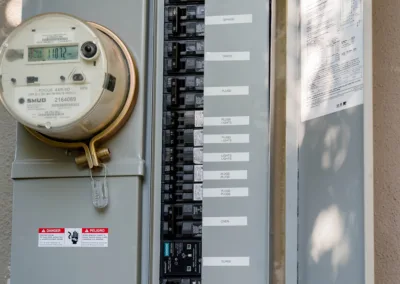 Electric utility meter and circuit breaker panel on a wall.