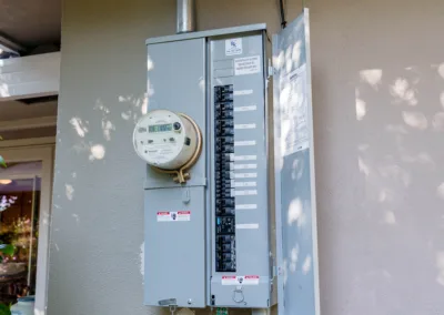 An electrical meter and circuit breaker box mounted on an exterior wall.