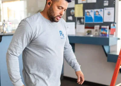 Man in a grey shirt inspecting a whiteboard in an office environment.