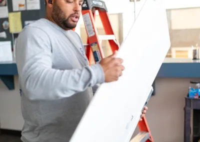 A man reviewing a large sheet of paper on an easel with a ladder in the background.