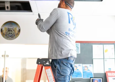 Man on a ladder repairing a ceiling tile.