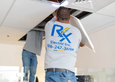 Electrician working on wiring in an open ceiling cavity.