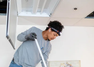 Man cleaning the floor with a mop under a partially opened drop ceiling.