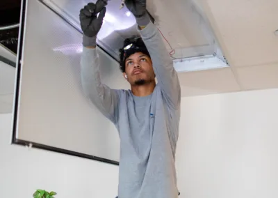 A man repairing ceiling lights while standing on a stool.