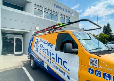 A commercial electrician service van parked in front of an office building bearing the 'teamsters' sign.