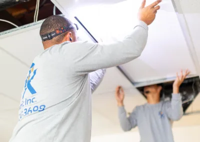 Two workers installing ceiling panels.